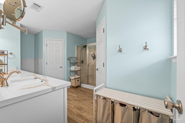 bathroom featuring vanity, wood-type flooring, a shower with shower door, and a textured ceiling