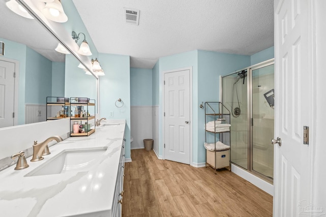 bathroom with vanity, an enclosed shower, hardwood / wood-style floors, and a textured ceiling