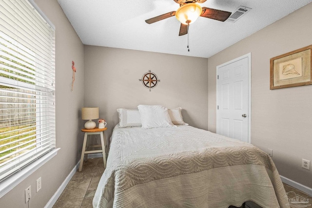 bedroom featuring light tile patterned flooring, ceiling fan, and multiple windows