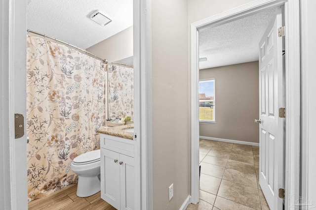 bathroom with vanity, toilet, wood-type flooring, and a textured ceiling