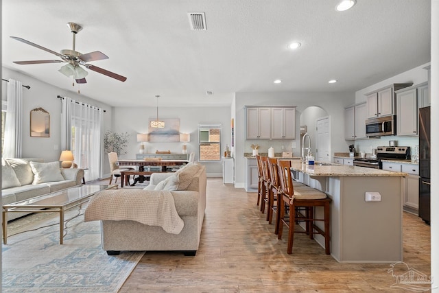6347 Ladera Trl, Pace, FL 32571 - living room with healthy amount of natural light, arched walkways, a ceiling fan, recessed lighting, and light wood-style flooring