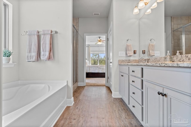 6347 Ladera Trl, Pace, FL 32571 - ensuite bathroom with wood finished floors, a stall shower, vanity, baseboards, and a garden tub