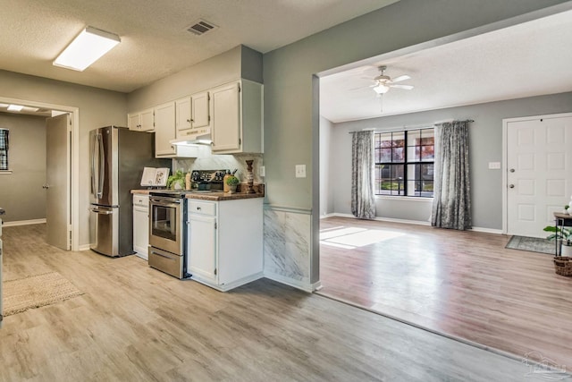 kitchen featuring appliances with stainless steel finishes, light wood-type flooring, a textured ceiling, and white cabinetry