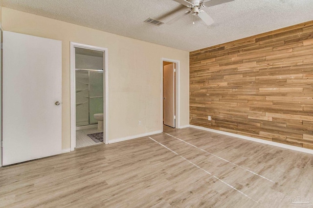 interior space featuring wooden walls, hardwood / wood-style floors, ceiling fan, and a textured ceiling