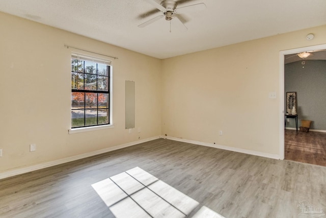 unfurnished room with ceiling fan, a textured ceiling, and light wood-type flooring