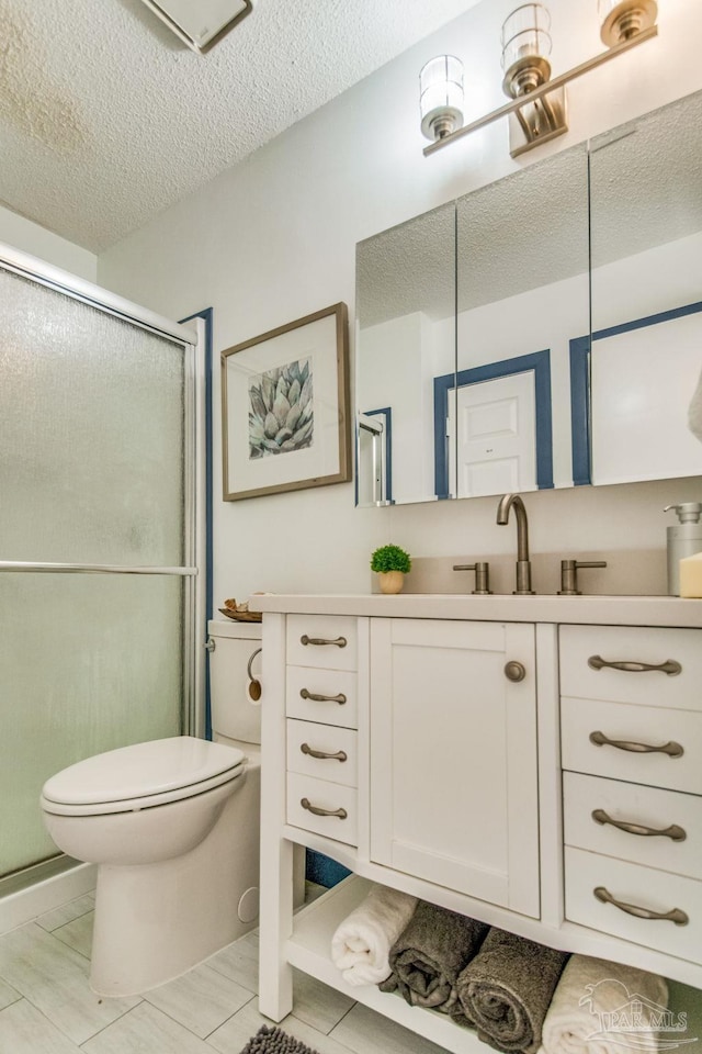 bathroom with vanity, a shower with shower door, a textured ceiling, and toilet