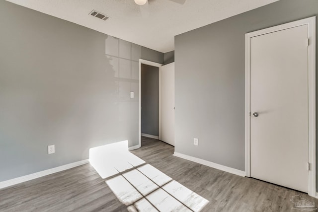 unfurnished room with a textured ceiling, light hardwood / wood-style floors, and ceiling fan