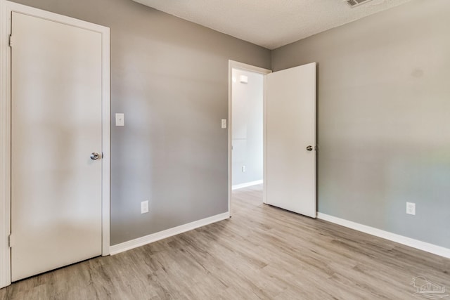 spare room featuring light hardwood / wood-style floors and a textured ceiling