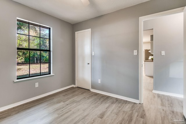 empty room featuring ceiling fan, a textured ceiling, and light hardwood / wood-style flooring