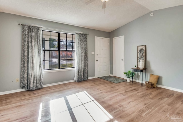 entrance foyer featuring a textured ceiling, light hardwood / wood-style flooring, ceiling fan, and lofted ceiling