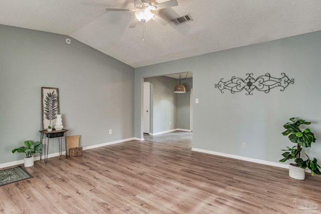 unfurnished room featuring hardwood / wood-style floors, a textured ceiling, ceiling fan, and lofted ceiling