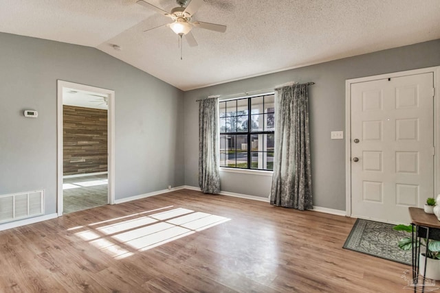 foyer with a textured ceiling, light hardwood / wood-style floors, vaulted ceiling, and ceiling fan