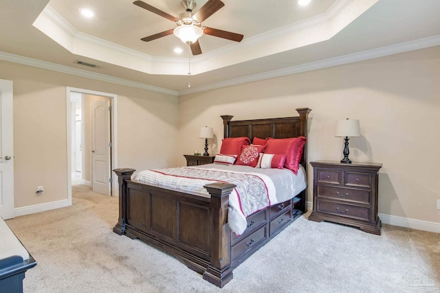 bedroom featuring crown molding, a tray ceiling, light carpet, and ceiling fan