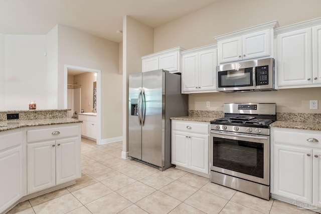 kitchen featuring white cabinets, light tile patterned flooring, appliances with stainless steel finishes, and light stone countertops