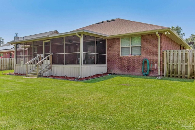 rear view of house featuring a lawn and a sunroom