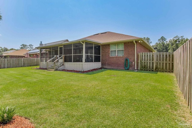 rear view of house with a lawn and a sunroom