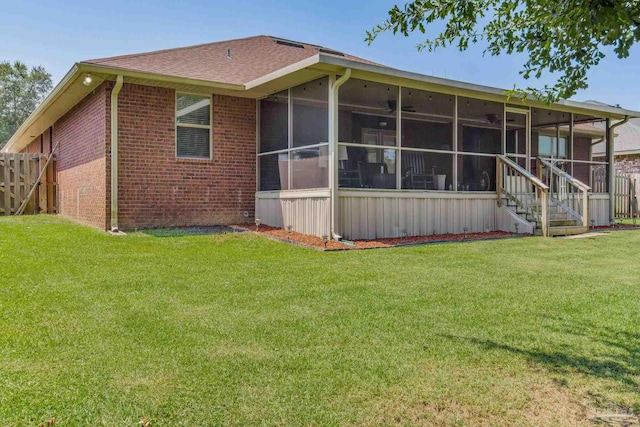 rear view of house featuring a sunroom and a lawn