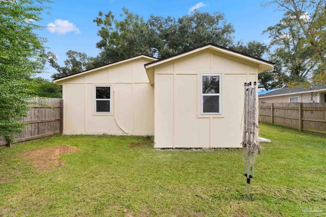 rear view of property with a lawn and a storage unit