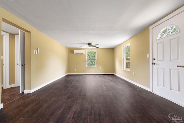 foyer with an AC wall unit, dark hardwood / wood-style flooring, ceiling fan, and plenty of natural light