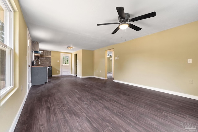 unfurnished living room featuring ceiling fan, dark hardwood / wood-style floors, a healthy amount of sunlight, and sink