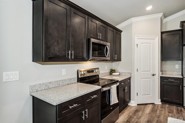 kitchen featuring hardwood / wood-style floors, crown molding, light stone countertops, dark brown cabinetry, and stainless steel appliances