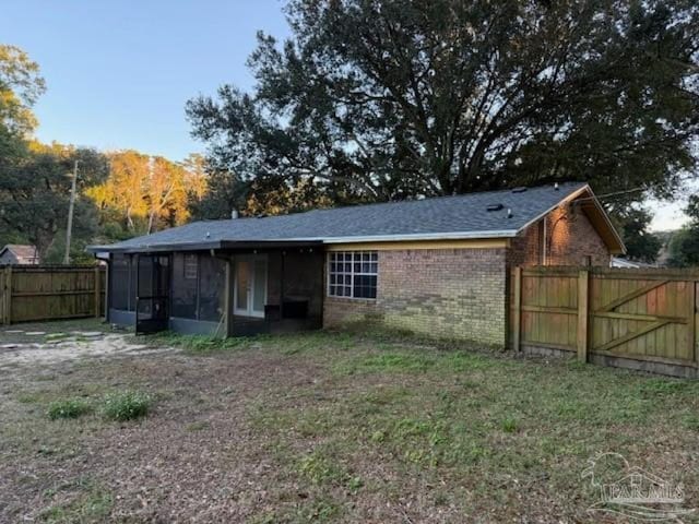 rear view of house featuring a yard and a sunroom