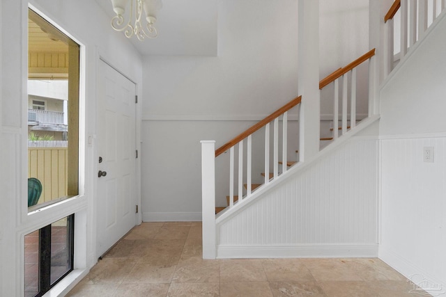 8520 Gulf Blvd Unit 23, Navarre Beach, FL 32566 - foyer featuring stairs, a chandelier, wainscoting, and a decorative wall