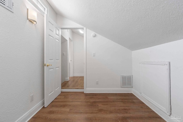 8520 Gulf Blvd Unit 23, Navarre Beach, FL 32566 - additional living space with lofted ceiling, a textured ceiling, dark wood-style flooring, and baseboards