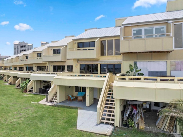 8520 Gulf Blvd Unit 23, Navarre Beach, FL 32566 - rear view of property featuring stairs, a patio area, metal roof, and a lawn