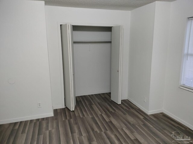 unfurnished bedroom with dark hardwood / wood-style floors, a closet, and a textured ceiling