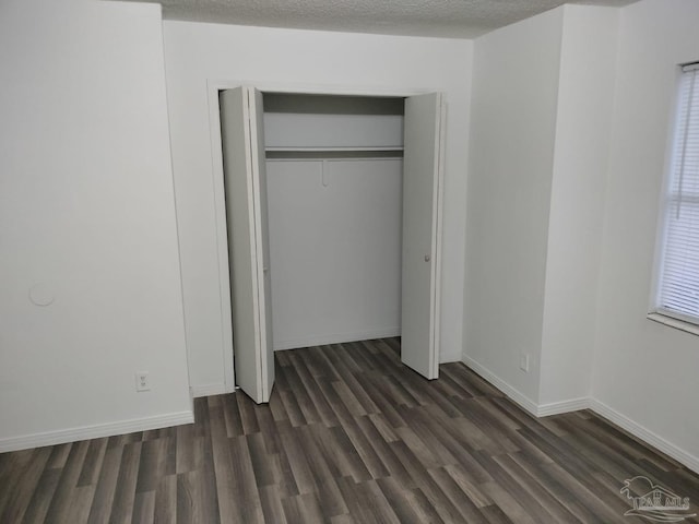 unfurnished bedroom with dark wood-type flooring, a closet, and a textured ceiling