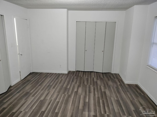 unfurnished bedroom with dark hardwood / wood-style flooring and a textured ceiling