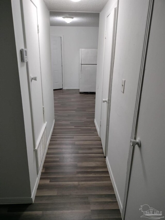 hall featuring dark wood-type flooring and a textured ceiling