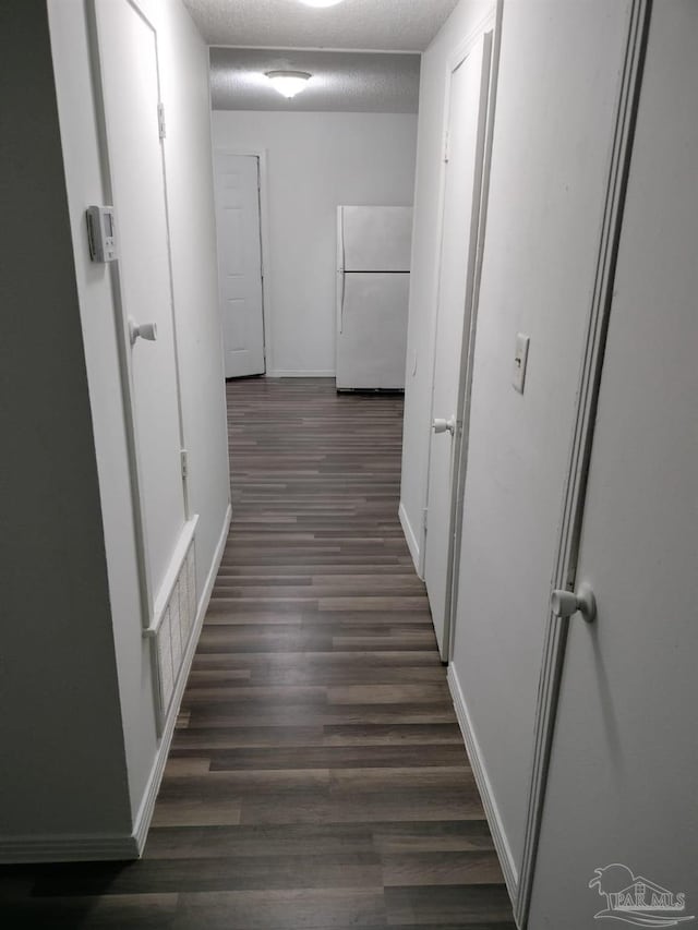 hall featuring a textured ceiling and dark hardwood / wood-style flooring