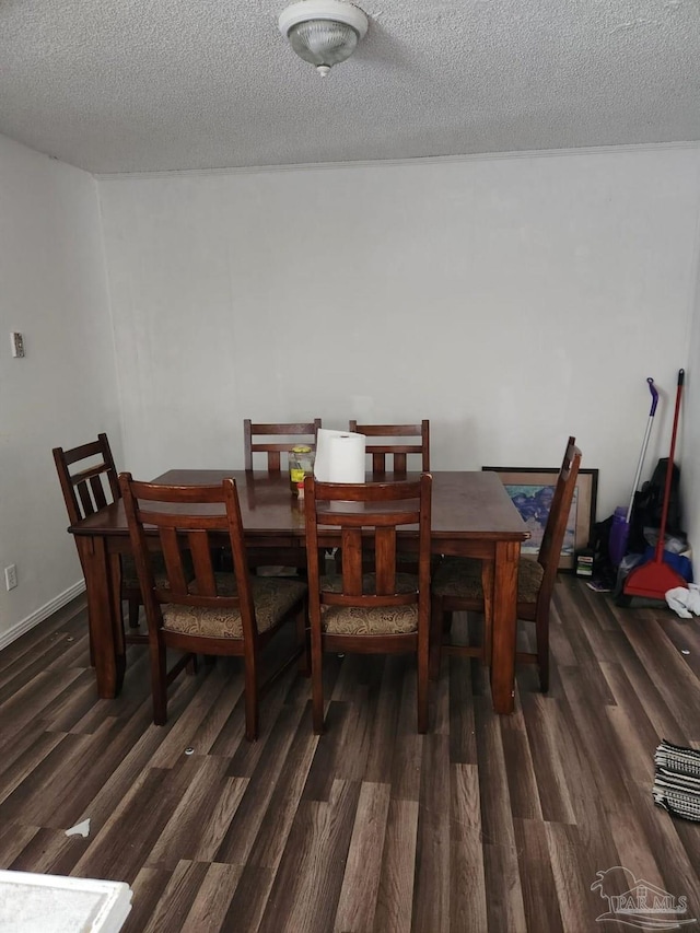 dining space featuring dark wood-type flooring and a textured ceiling