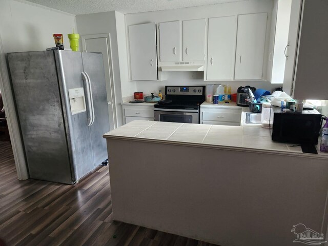 kitchen with appliances with stainless steel finishes, dark hardwood / wood-style flooring, tile counters, and white cabinets