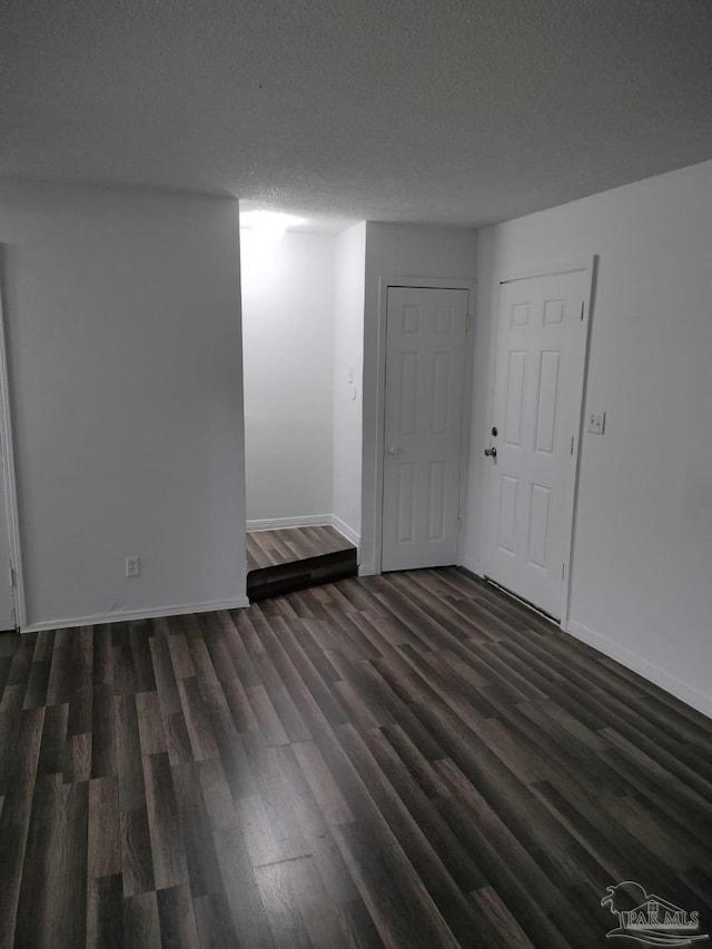 unfurnished room with a textured ceiling and dark hardwood / wood-style flooring