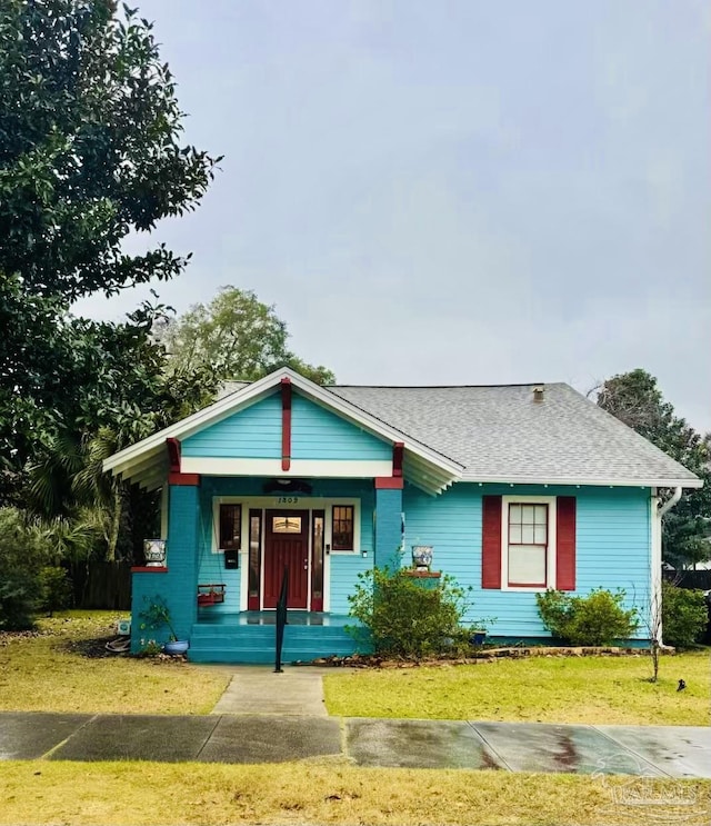 bungalow-style house with a front lawn and covered porch