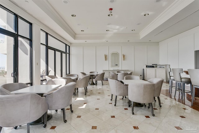 dining area featuring light tile patterned floors, a raised ceiling, and crown molding