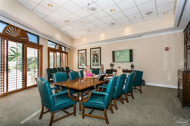 dining room with carpet flooring, a raised ceiling, and a paneled ceiling