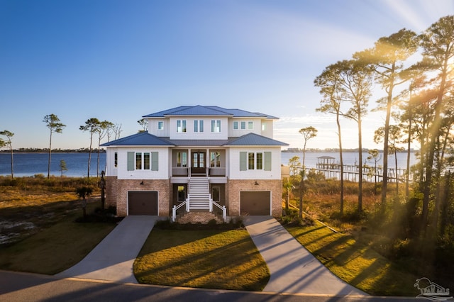 view of front of home featuring a garage, a water view, and a yard