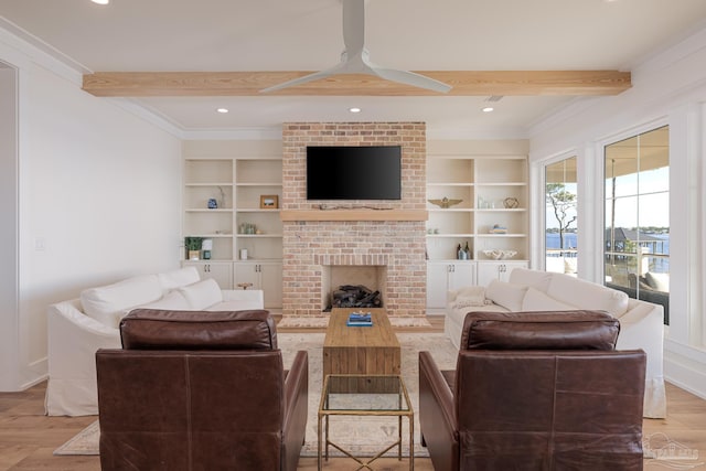 living room featuring a brick fireplace, built in shelves, ceiling fan, beamed ceiling, and light hardwood / wood-style floors