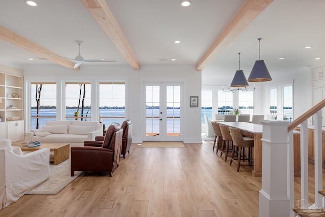 living room featuring a wealth of natural light, ceiling fan, french doors, beamed ceiling, and a water view