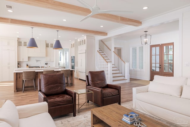 living room featuring beam ceiling, a chandelier, french doors, and light hardwood / wood-style floors