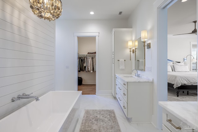 bathroom featuring a chandelier, vanity, and a tub to relax in