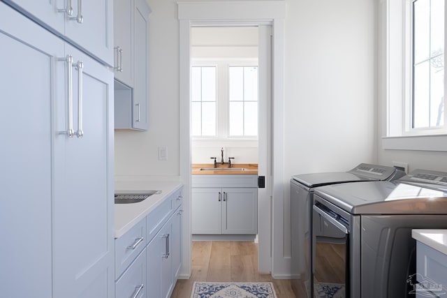 laundry room featuring cabinets, separate washer and dryer, light hardwood / wood-style floors, and sink