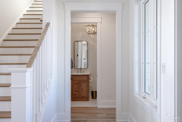 stairway featuring wood-type flooring, an inviting chandelier, and sink