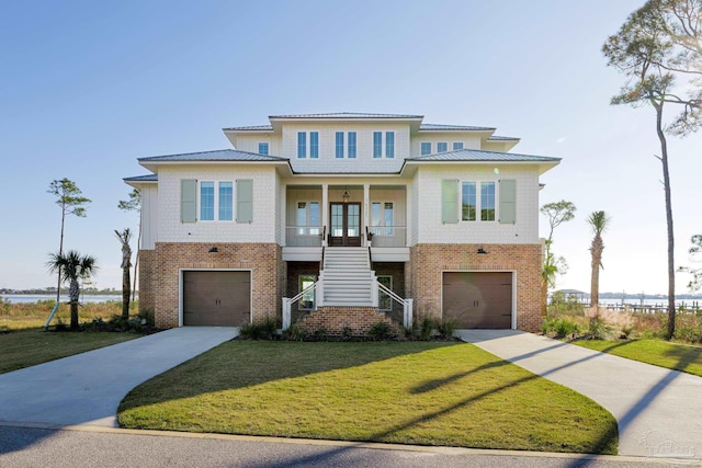 view of front facade with a porch, a garage, french doors, and a front lawn