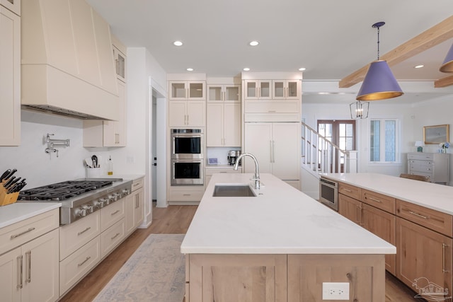 kitchen with pendant lighting, a large island with sink, sink, appliances with stainless steel finishes, and beam ceiling