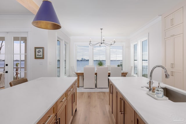 kitchen with sink, pendant lighting, a water view, a chandelier, and light hardwood / wood-style floors